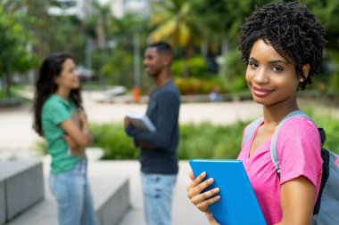 Bir grup arkadaşıyla birlikte gülen Brezilyalı kız öğrenci Tropikal şehirde