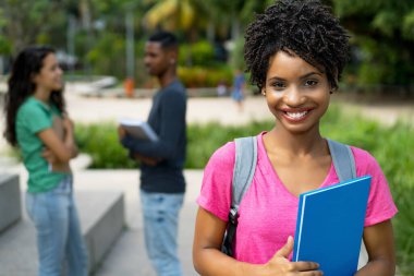 Tropikal şehirde bir grup arkadaşıyla gülen Brezilyalı kız öğrenci.