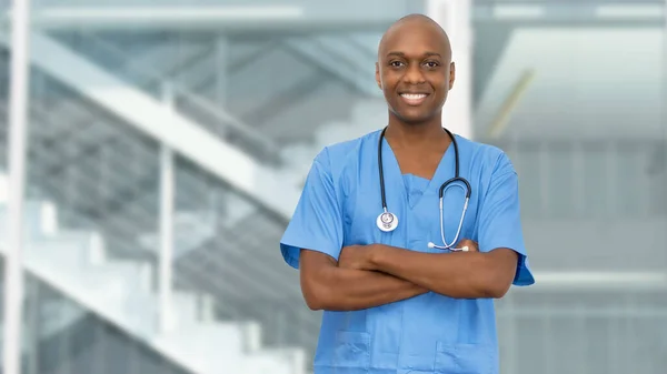 Handsome black doctor or male nurse with crossed arms at hospital