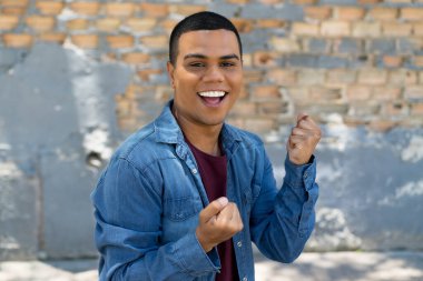 Cheering mexican young adult man outdoor in urban style