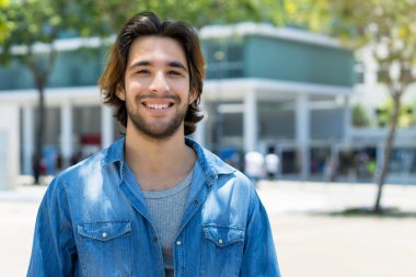 Handsome mexican young adult man with beard outdoor in summer in city