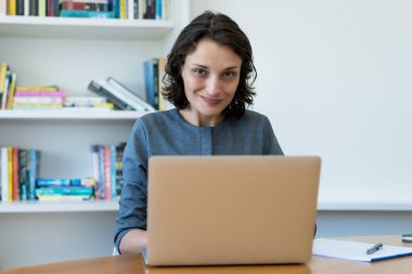 Kafkasyalı, olgun bir iş kadını ofiste bilgisayar başında çalışıyor.