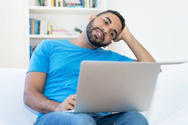 Latin american man streaming romantic movie online at computer indoors at home