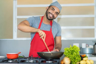 Hispanic kitchen assistant making meal at restaurant clipart