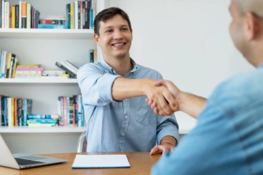 Handshake of motivated software engineer after succesful job interview at desk at office