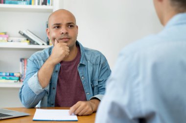 Thinking IT specialist at job interview with businessman at desk at office
