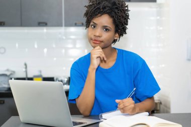 Portrait of learning african american female student at computer indoors at desk at home