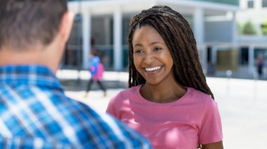 Rasta bukleli güzel siyahi kadın yazın erkek arkadaşıyla dışarıda flört ediyor ve konuşuyor.