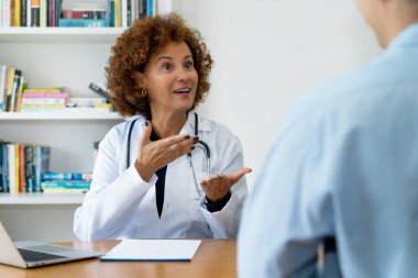 Hastanedeki hastaya iyi haberlerle gülen olgun bayan doktor.