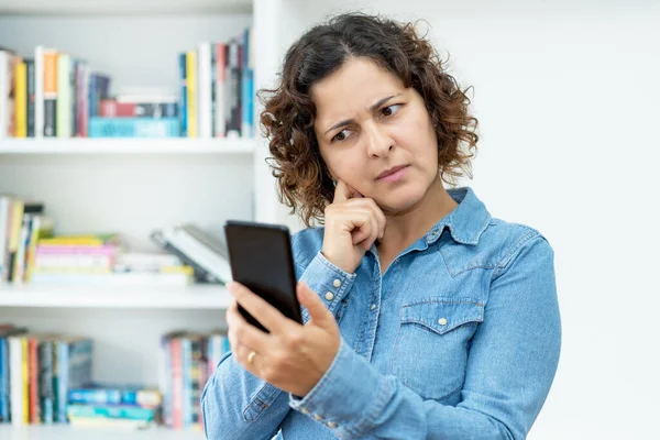 Gammal Kvinna Läser Ett Förvirrande Meddelande Mobiltelefon Inomhus — Stockfoto