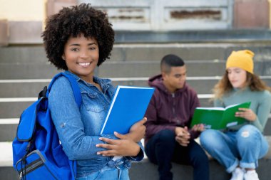 Kentsel şehir tarzında Latin kökenli genç yetişkinlerle güzel bir Afrikalı Amerikalı kız öğrenci.