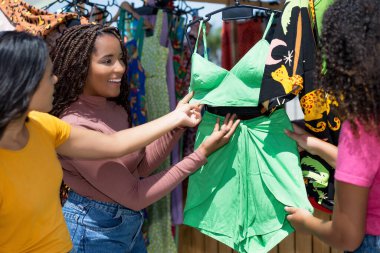 Bir grup Afro-Amerikan ve İspanyol genç yetişkin bit pazarından ya da yazın açık havada renkli kıyafetler alıyorlar.