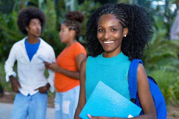 Laughing african american female student with group of black young adults outdoors in summer
