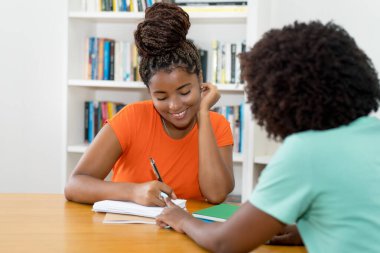 Afrika kökenli Amerikalı kız öğrenci üniversite sınıfında özel olarak sınava hazırlanıyor.