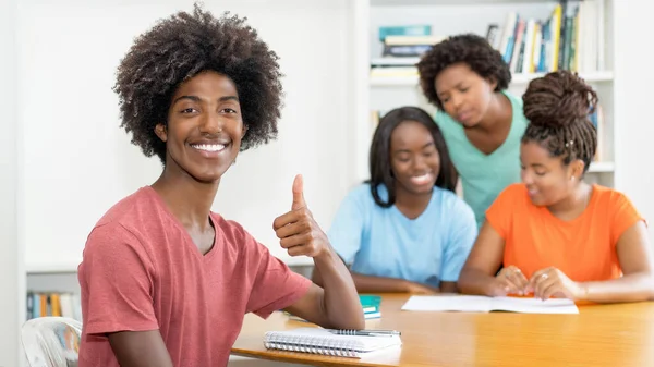 成功的黑人男生在课桌前与一群学习的非洲裔美国学生在大学课堂上 — 图库照片