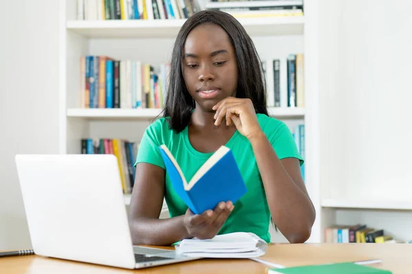 Kitap Bilgisayarla Kütüphanede Akıllı Siyah Kız Öğrenci Öğreniyor — Stok fotoğraf