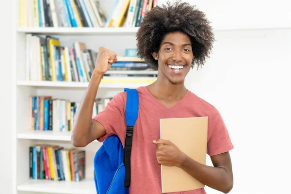 大学の教室でカメラを眺めるバックパックと書類ワークを持つアフリカ系アメリカ人の男性学生を応援する成功 — ストック写真