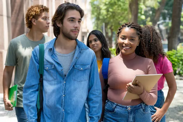 African american female student and hispanic male student walking to university outdoor in city in summer