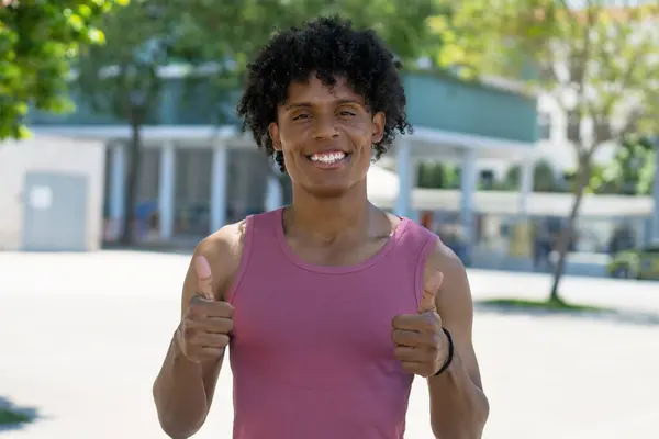 今年夏天 在城市里 一个肌肉丰满的美国男人在户外竖起大拇指 图库图片