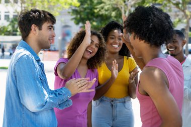 Latin Amerikalı ve Kafkasyalı genç yetişkinler, yaz aylarında şehir dışında siyahi erkek öğrencilerin başarısını kutluyorlar.