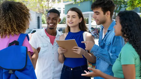 Group of laughing caucasian and latin american and black male and female students outdoor in summer in city