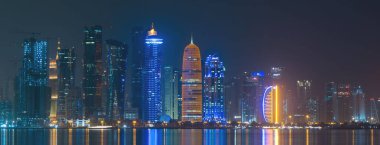 Doha, Katar - Eylül 09.2022: Doha şehir merkezinin gece boyunca pek çok iş kulesi ile canlı bir silueti.