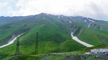 Kazbek dağlarındaki çimenli tepeden panoramik manzara ve yeşil vadi yollarla kesişiyor.