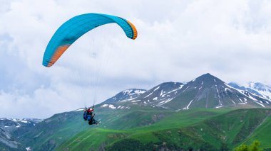 Tiflis, Gürcistan-Haziran 06.2024: Kazbegi dağları arasında yamaç paraşütü yapan insanlar.