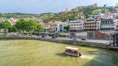Tiflis, Gürcistan - 6 Haziran 2024: Tiflis şehrinin keşfi, nehir boyunca kentsel zevkler ve manzaralı tekne yolculuklarını da içeriyor ve ziyaretçiler için çok yönlü bir deneyim sunuyor.