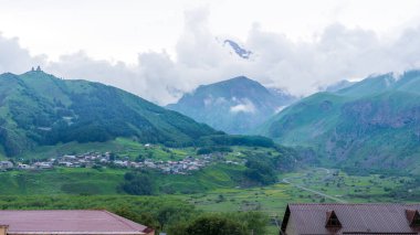 Kazbek dağlarındaki çimenli tepeden panoramik manzara ve yeşil vadi yollarla kesişiyor.