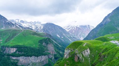 Kazbek dağlarındaki çimenli tepeden panoramik manzara ve yeşil vadi yollarla kesişiyor.