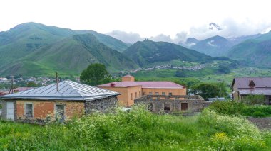 Panoramic view from the grassy hill on the Kazbek mountains and the green valley crossed with roads clipart