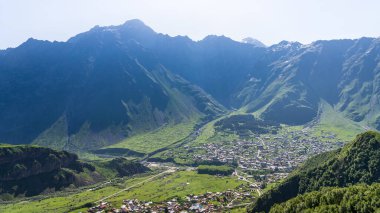 Kazbek dağlarındaki çimenli tepeden panoramik manzara ve yeşil vadi yollarla kesişiyor.