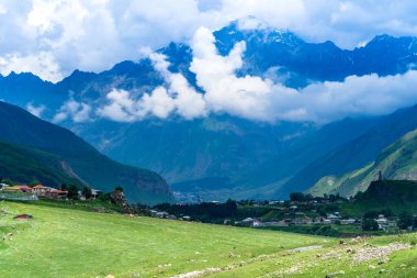 Kazbek dağlarındaki çimenli tepeden panoramik manzara ve yeşil vadi yollarla kesişiyor.