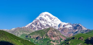 Kazbek dağlarındaki çimenli tepeden panoramik manzara ve yeşil vadi yollarla kesişiyor.