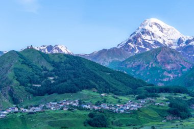 Kazbek dağlarındaki çimenli tepeden panoramik manzara ve yeşil vadi yollarla kesişiyor.