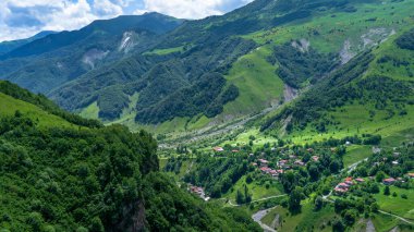 Kazbek dağlarındaki çimenli tepeden panoramik manzara ve yeşil vadi yollarla kesişiyor.