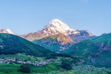 Kazbek dağlarındaki çimenli tepeden panoramik manzara ve yeşil vadi yollarla kesişiyor.