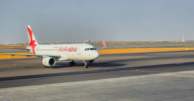 Doha, Katar, 12 Ekim 2024: Sharjah Havaalanı, BAE 'de Air Arabia uçağı yolcu alımı ve havayolunun imzalı kırmızı ve beyaz üniformasıyla pistte sergilenmektedir..