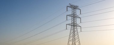Yüksek voltajlı elektrik hatlarını destekleyen yüksek elektrik kuleleri ufuk çizgisi boyunca uzanıyor. Yapılar güç transferi için çok önemli..