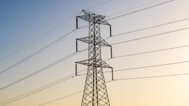 Yüksek voltajlı elektrik hatlarını destekleyen yüksek elektrik kuleleri ufuk çizgisi boyunca uzanıyor. Yapılar güç transferi için çok önemli..