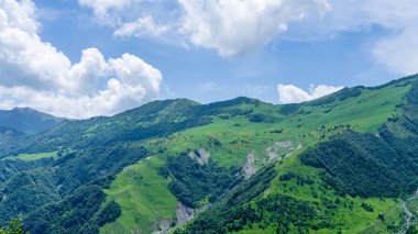 Kazbek dağlarındaki çimenli tepeden panoramik manzara ve yeşil vadi yollarla kesişiyor.