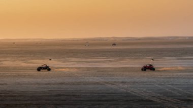 Doha, Katar-22 Ocak 2025: Sealine Çölü 'nde, arazi araçlarının altın kum tepeleri altında hızla ilerlediği heyecan verici bir kum tepeciği deneyimi.