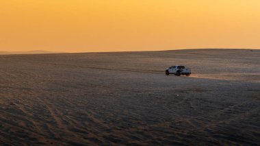 Doha, Katar-22 Ocak 2025: Sealine Çölü 'nde, arazi araçlarının altın kum tepeleri altında hızla ilerlediği heyecan verici bir kum tepeciği deneyimi.