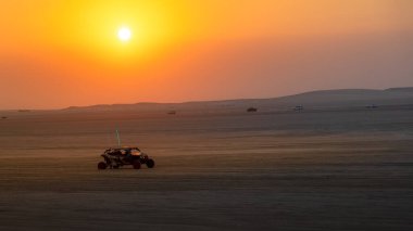 Doha, Katar-22 Ocak 2025: Sealine Çölü 'nde, arazi araçlarının altın kum tepeleri altında hızla ilerlediği heyecan verici bir kum tepeciği deneyimi.