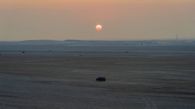 Doha, Katar-22 Ocak 2025: Sealine Çölü 'nde, arazi araçlarının altın kum tepeleri altında hızla ilerlediği heyecan verici bir kum tepeciği deneyimi.