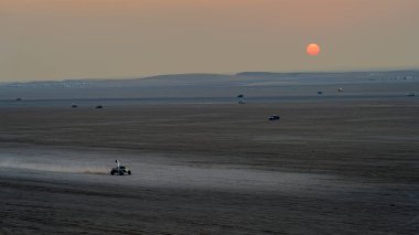 Doha, Katar-22 Ocak 2025: Sealine Çölü 'nde, arazi araçlarının altın kum tepeleri altında hızla ilerlediği heyecan verici bir kum tepeciği deneyimi.
