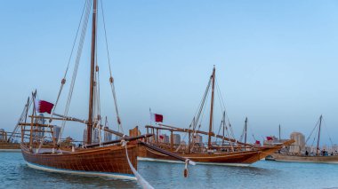 Doha, Katar-22 Ocak 2025: Katar 'ın deniz mirasının simgesel bir sembolü olan geleneksel bir balıkçı teknesi, arka planda Doha silueti ile Basra Körfezi' nin berrak sularında yüzüyor..