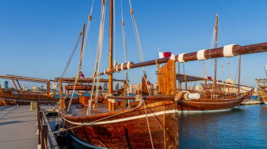 Doha, Katar-22 Ocak 2025: Katar 'ın deniz mirasının simgesel bir sembolü olan geleneksel bir balıkçı teknesi, arka planda Doha silueti ile Basra Körfezi' nin berrak sularında yüzüyor..