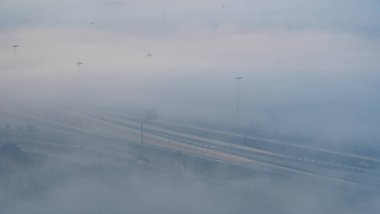 Lusail, Katar - 24 Şubat 2025: Lusail 'de sisle kaplı bir otoyol, düşük görüş mesafesi ve parıldayan sokak lambalarıyla gizemli bir atmosfer yaratıyor..